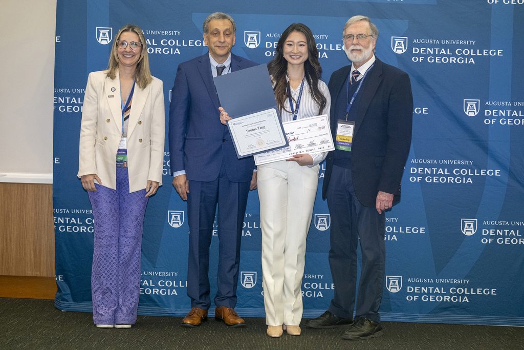 Winner holds award next to presenters.
