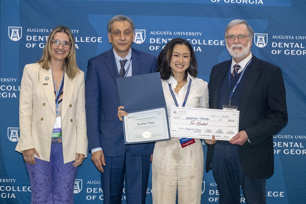 Winner holds award next to presenters.