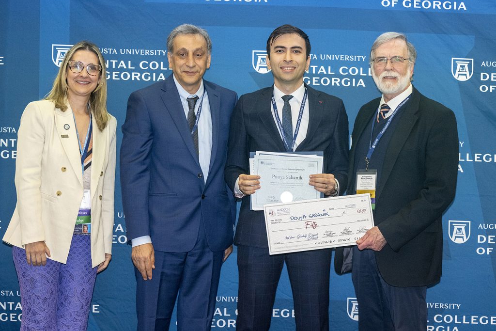 Winner holds award next to presenters.