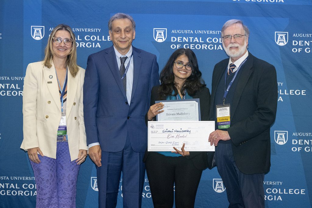 Winner holds award next to presenters.