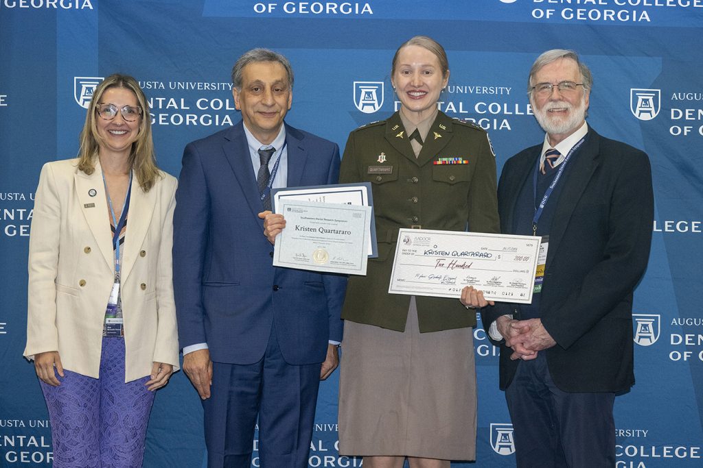 Winner holds award next to presenters.