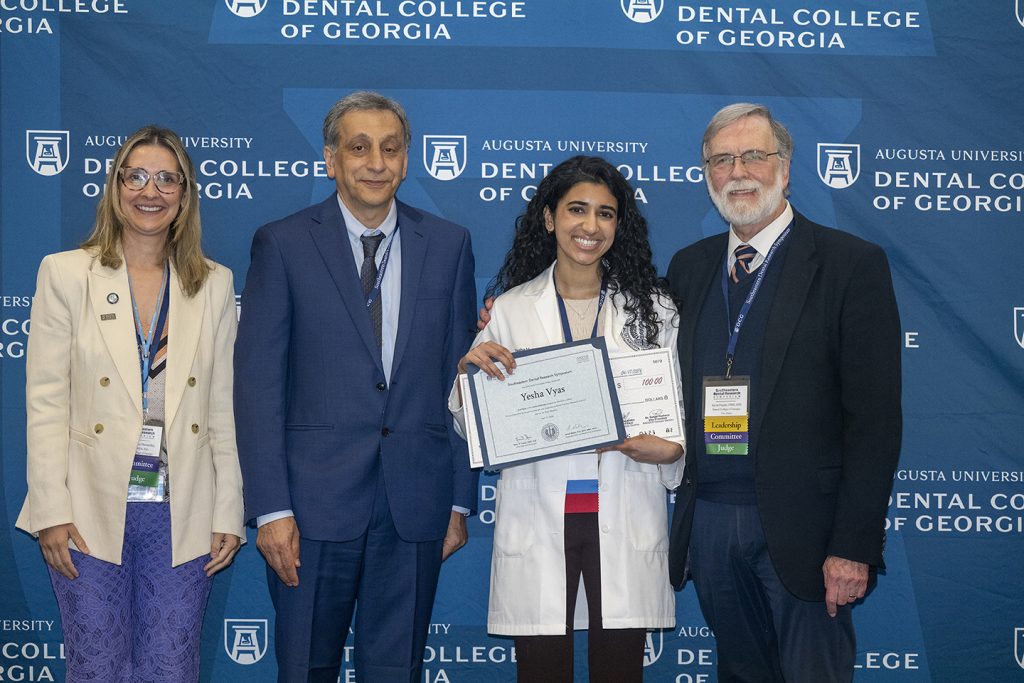 Winner holds award next to presenters.