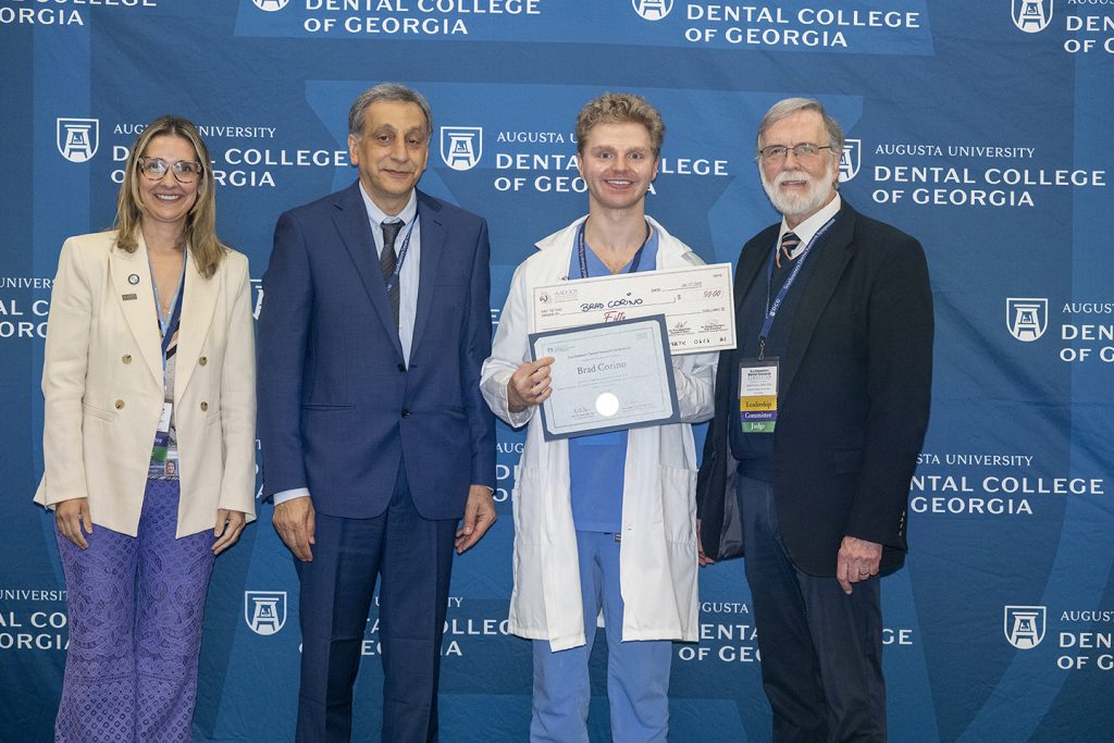 Winner holds award next to presenters.