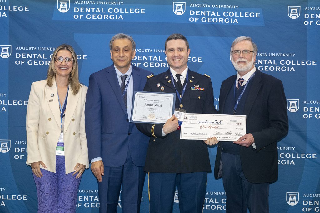 Winner holds award next to presenters.