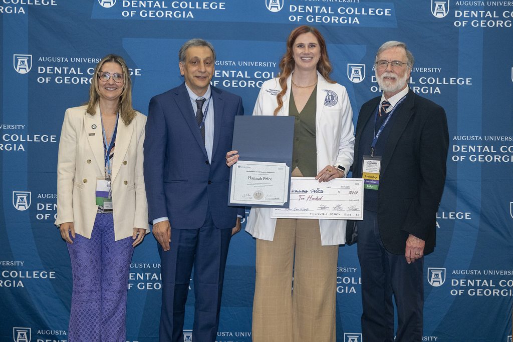 Winner holds award next to presenters.