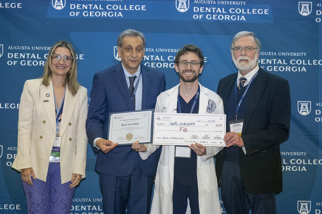 Winner holds award next to presenters.