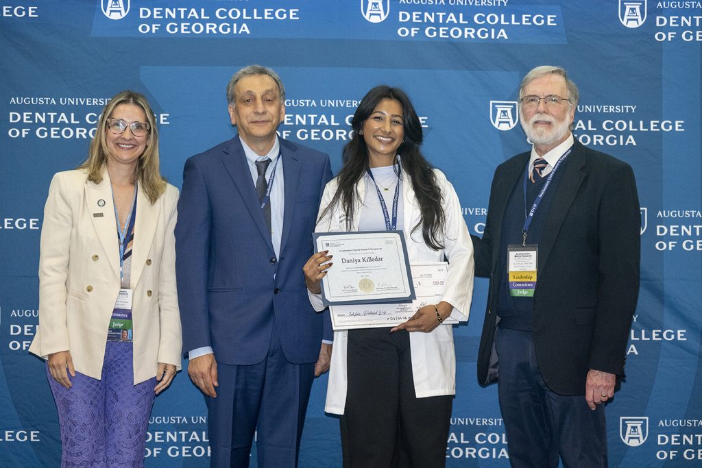 Winner holds award next to presenters.