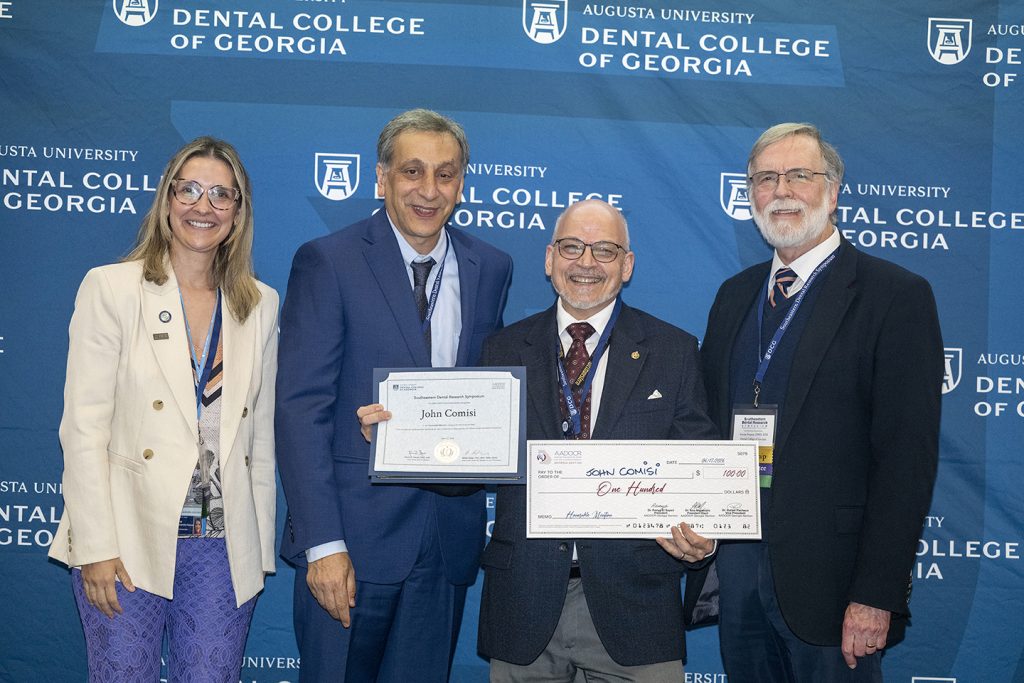 Winner holds award next to presenters.